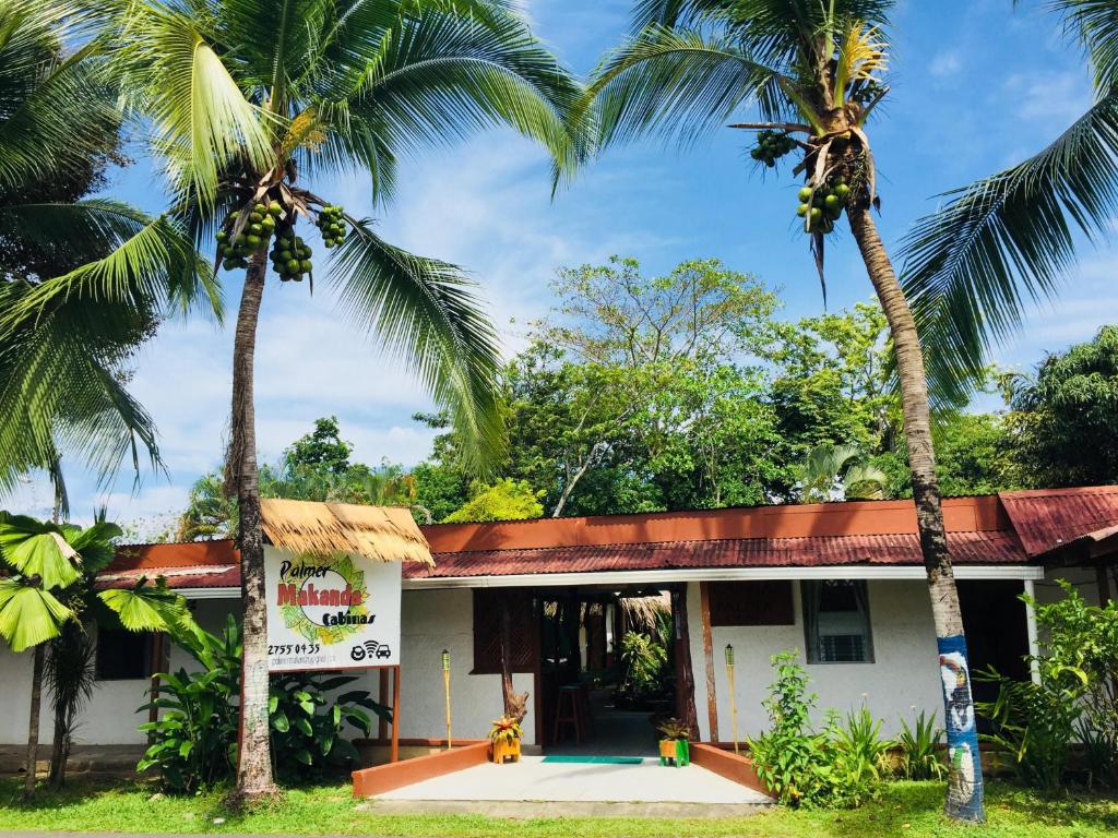 a building with two palm trees in front of it at Cabinas Palmer Makanda in Cahuita