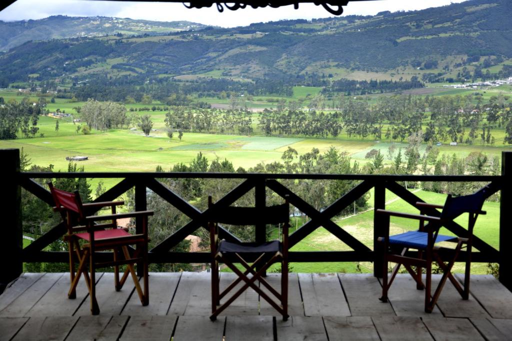 2 sillas en un porche con vistas a las montañas en El Pedregal Sopó, en Sopó