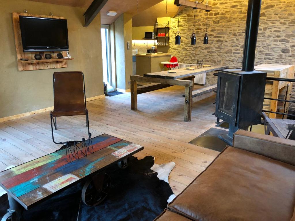 a living room with a wood stove and a table at L'Annexe in Halleux