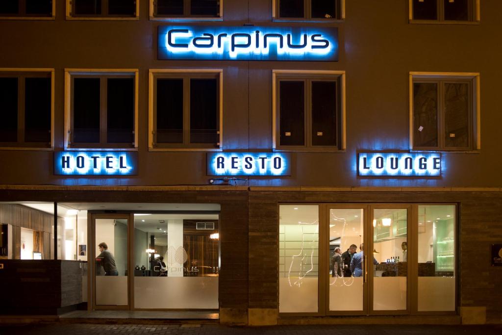 una tienda con letreros de neón al lado de un edificio en Hotel Carpinus, en Lovaina