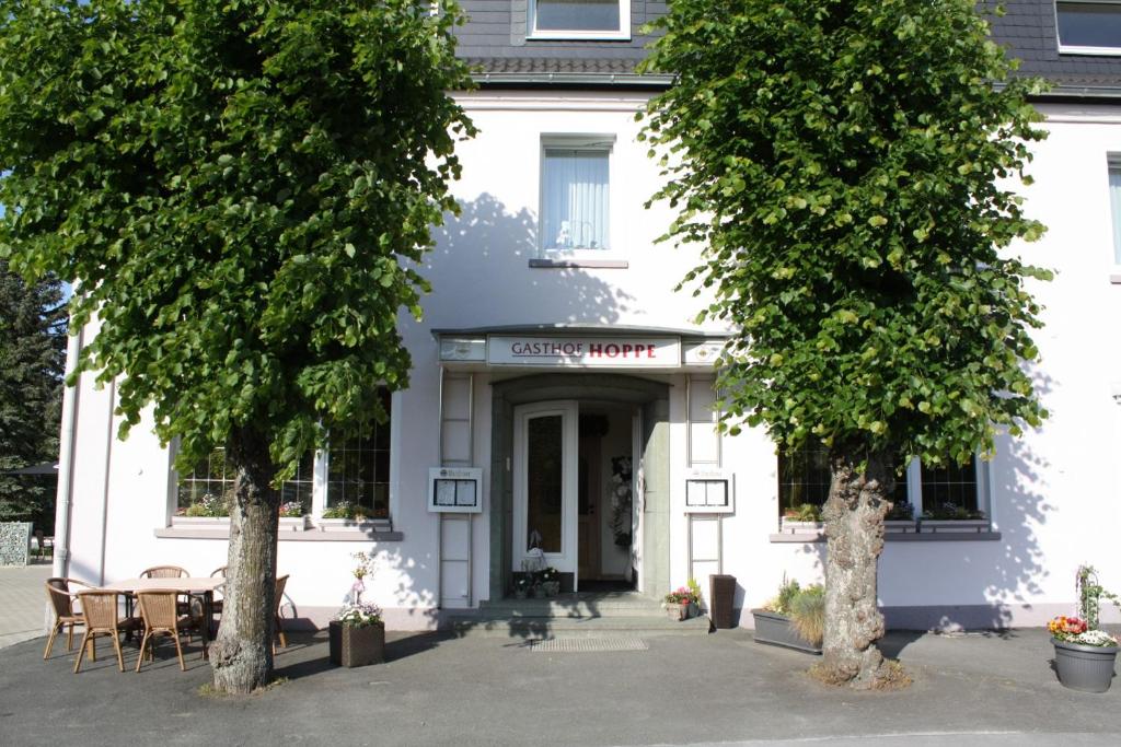 een wit gebouw met bomen ervoor bij Gasthof Hoppe in Warstein