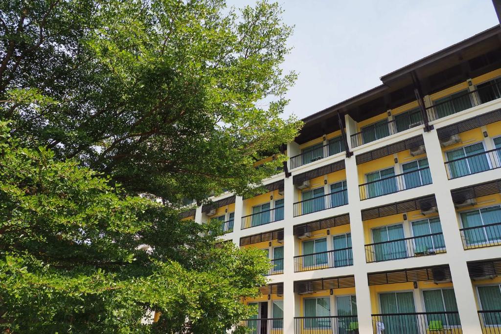 een appartementencomplex met een boom ervoor bij Sakorn Residence and Hotel in Chiang Mai