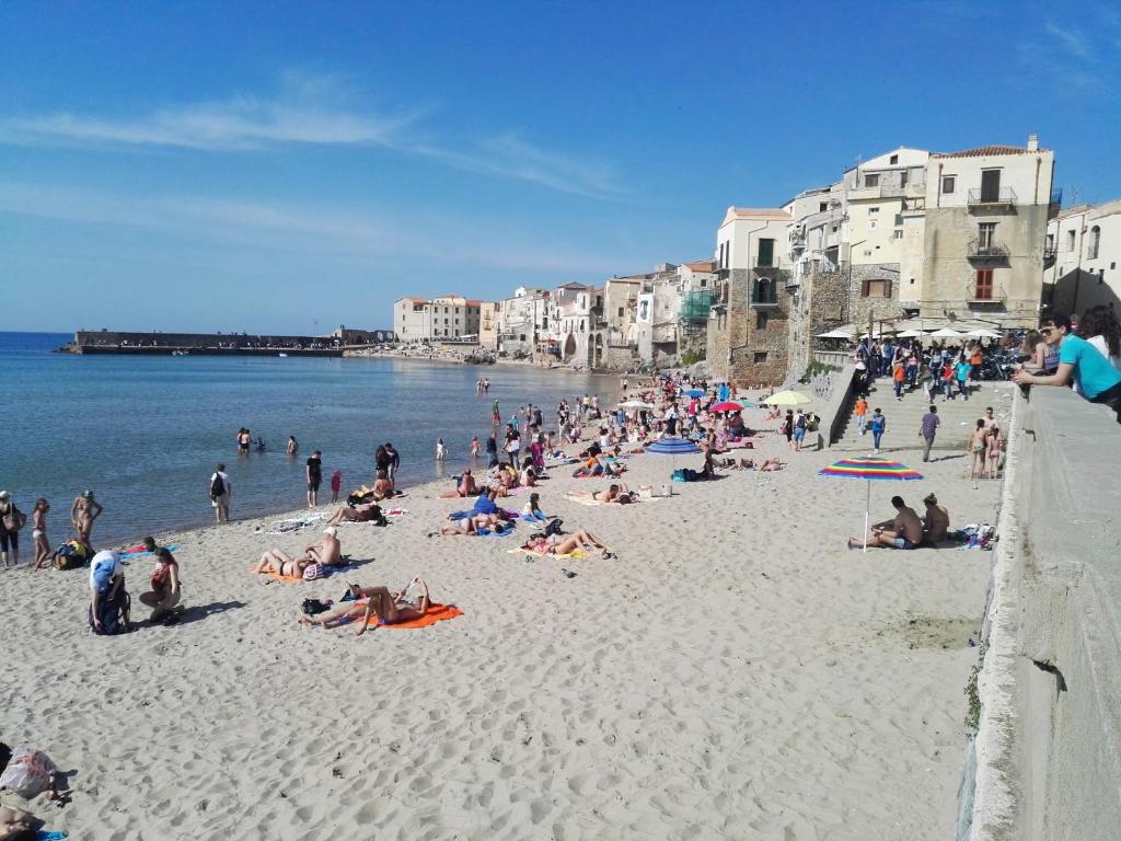 un groupe de personnes sur une plage près de l'eau dans l'établissement casa nica sul mare house on the sea, à Cefalù