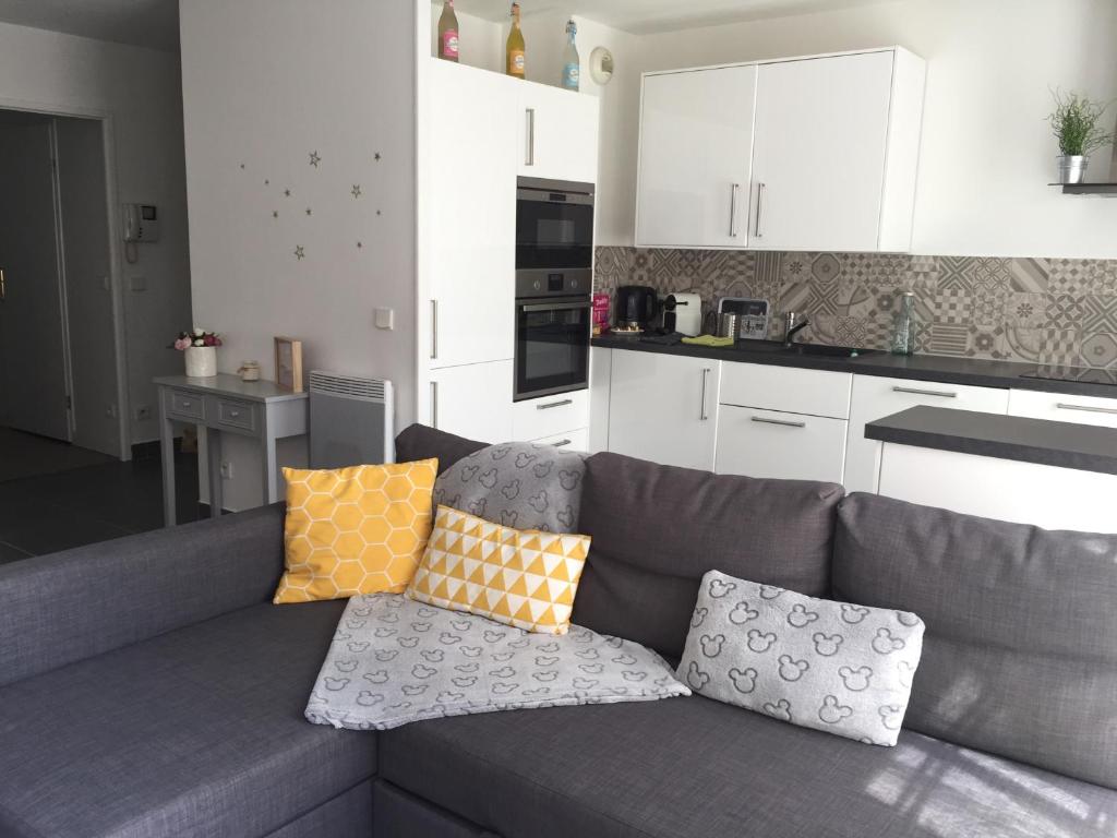 a grey couch with pillows on it in a kitchen at Julie's Homes Disneyland in Serris