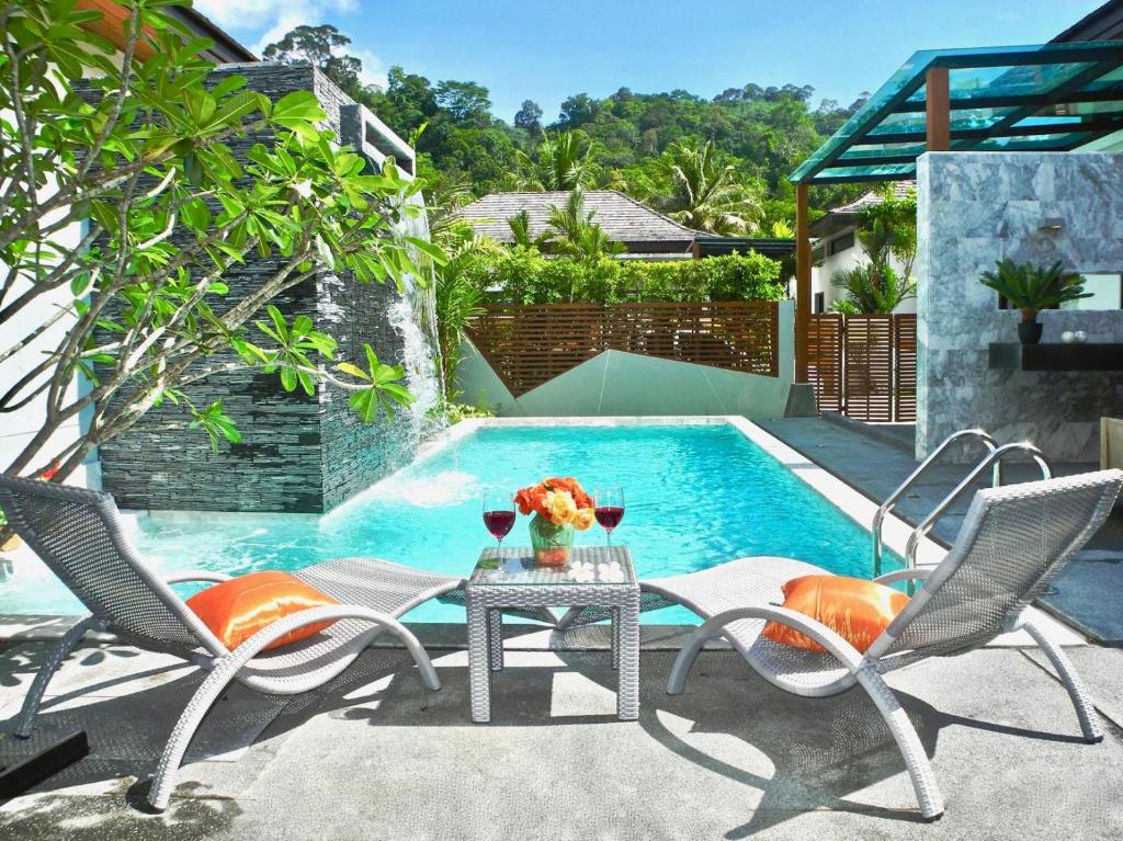 a pool with two chairs and a table with flowers on it at Coco Kamala: Breathtaking villa in Kamala Beach