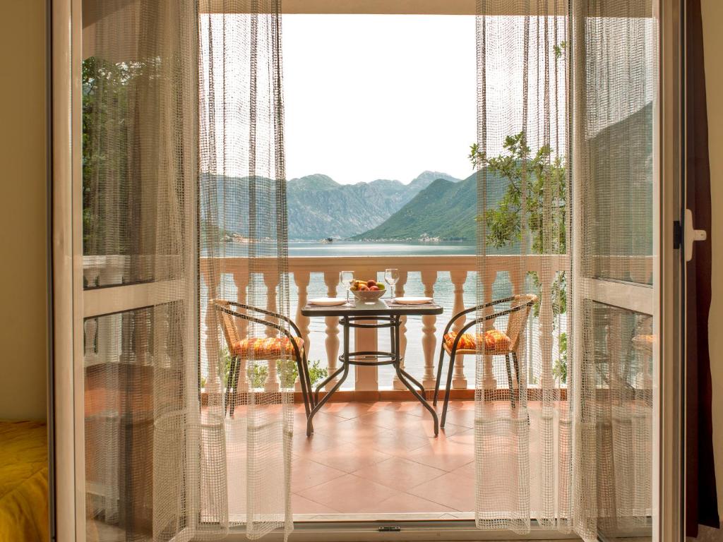 a room with a table and chairs on a balcony at Apartments Radonic in Donji Morinj