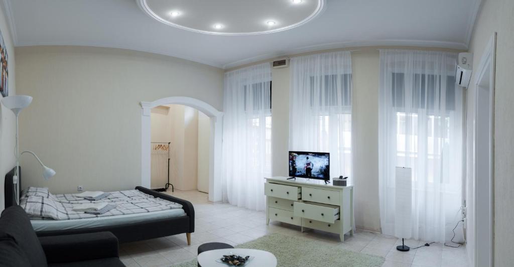 a bedroom with a bed and a dresser with a television at MainStreet apartman in Subotica