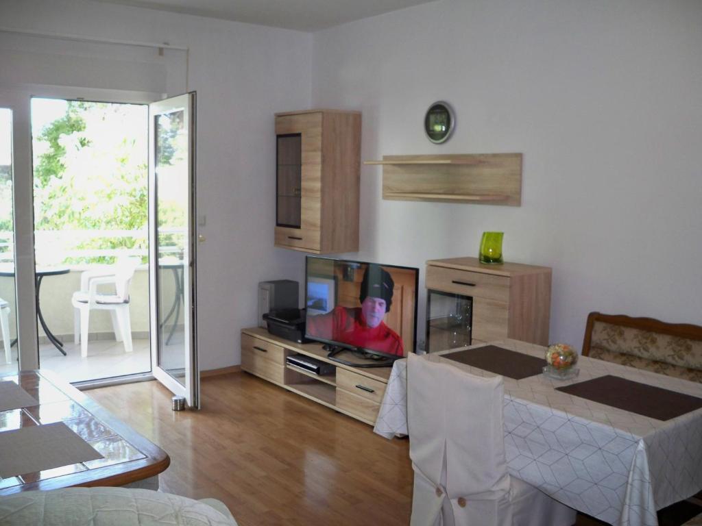 a living room with a television and a man in a hat at Apartmani Perkovic in Baška Voda