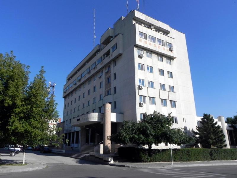 un grand bâtiment blanc avec un arbre en face dans l'établissement Hotel Calarasi, à Călăraşi