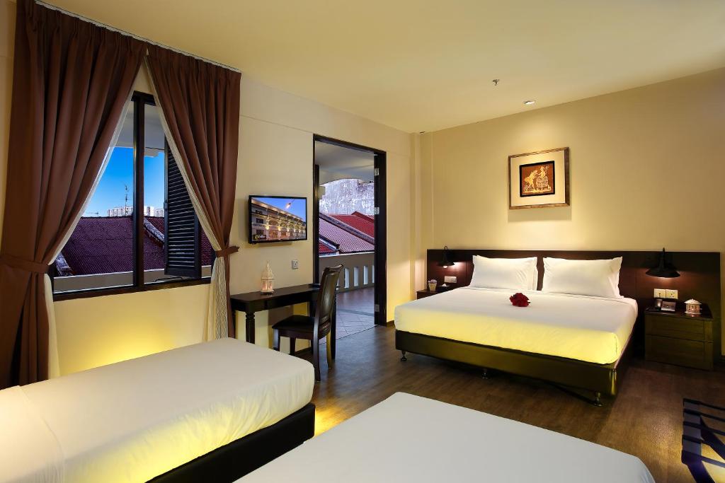 a hotel room with two beds and a desk and a window at Kimberley Hotel Georgetown in George Town