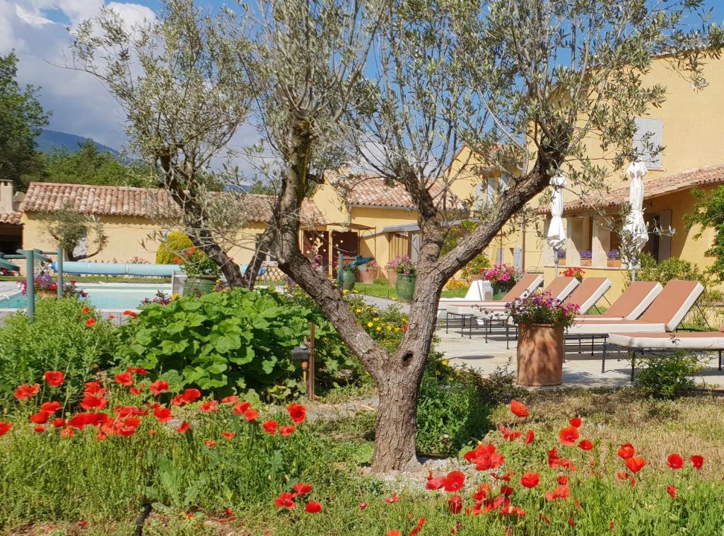 un jardín con flores rojas frente a una casa en La Grande Bouisse, en Céreste