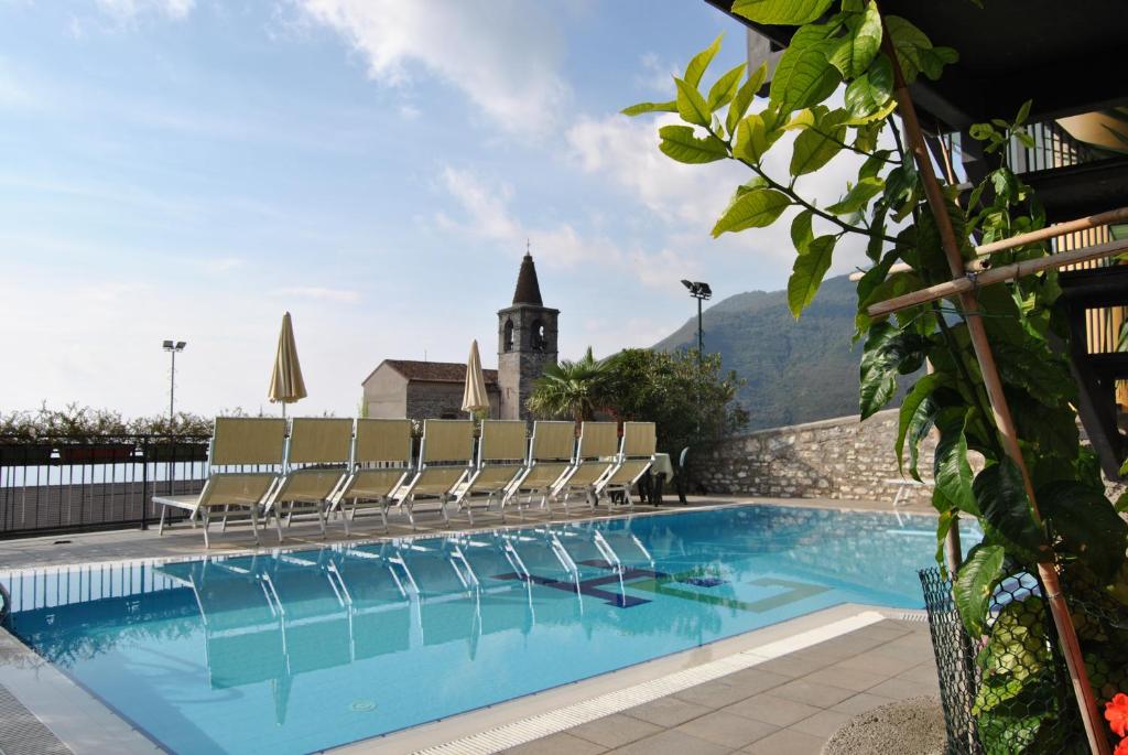 a large swimming pool with chairs and a building at Hotel Gallo in Tignale