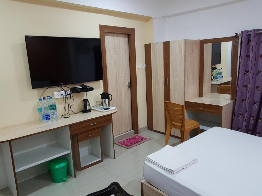 a room with a desk with a television and a bed at Jimmy Guest House in Kolkata