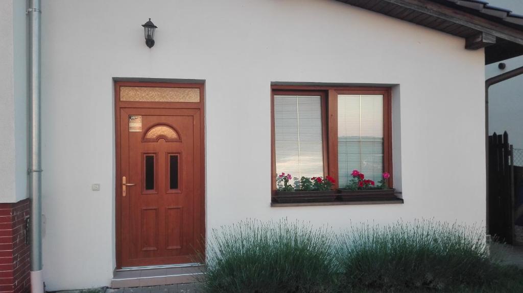 een huis met een rode deur en twee ramen bij Apartmán Eva in Vrbovec