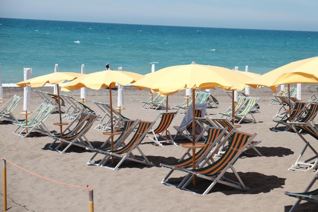 eine Gruppe von Stühlen und Sonnenschirmen am Strand in der Unterkunft Camping Casa Di Caccia in Marina di Bibbona