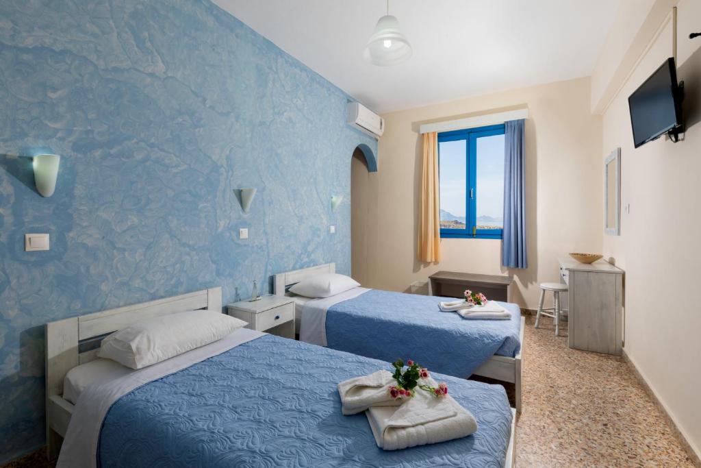 two beds in a room with blue walls at Vassos Apartments in Lindos