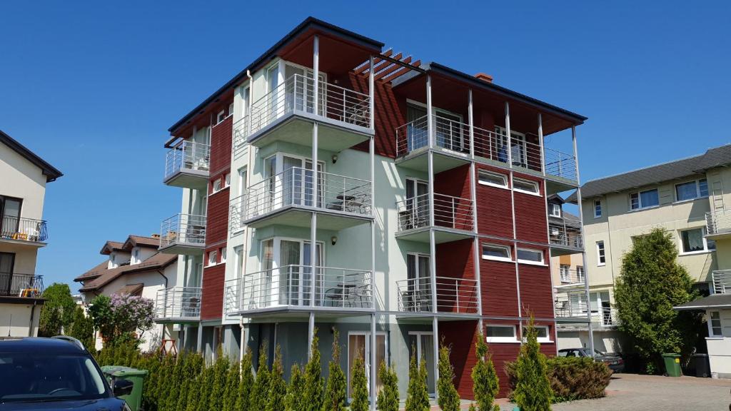 an apartment building with red and white balconies at Riwiera in Mielno