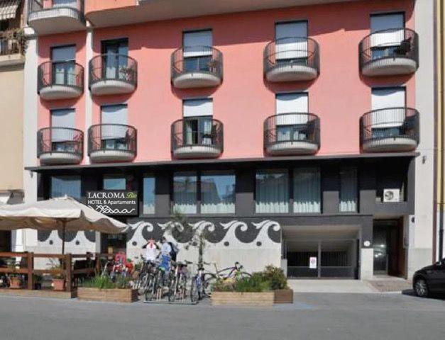 un edificio rosa con balcones y bicicletas delante de él en Lacroma Bio Hotel & Apartments, en Grado