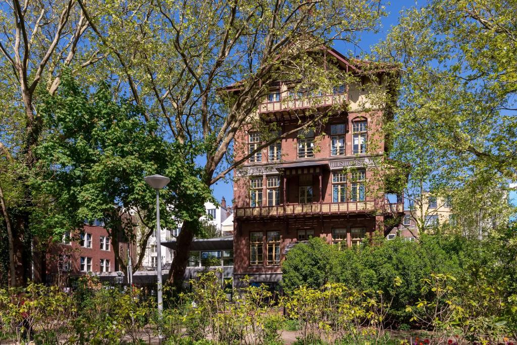 an old brick building in the middle of a garden at Stayokay Hostel Amsterdam Vondelpark in Amsterdam