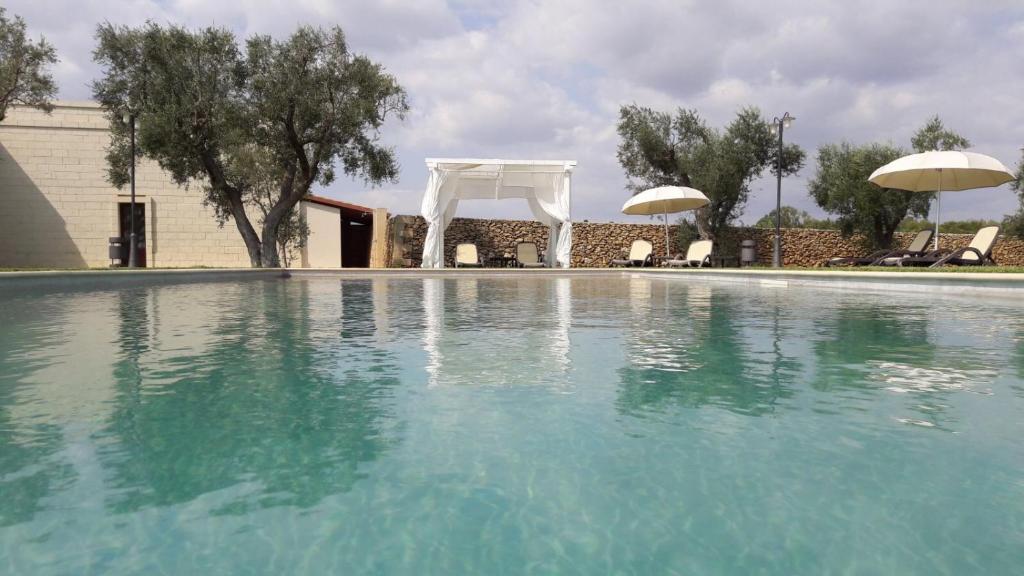 a swimming pool with a white arch and a wedding marquee at Masseria San Polo in Squinzano