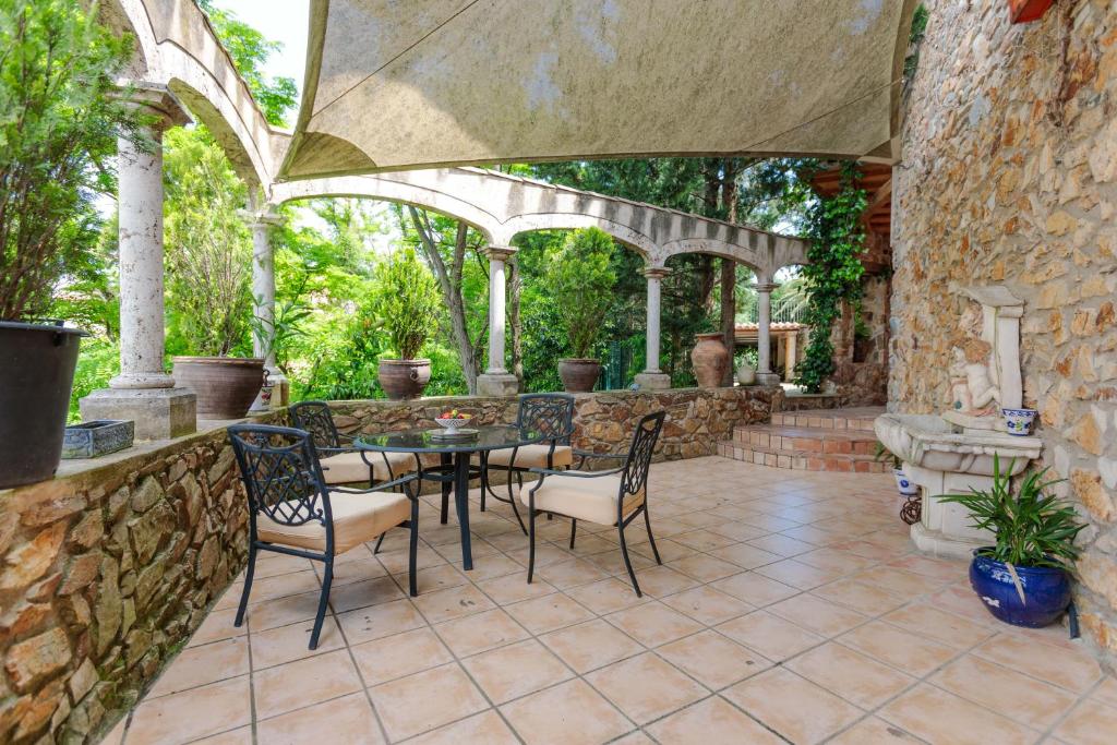 eine Terrasse mit einem Tisch, Stühlen und einer Steinmauer in der Unterkunft Flateli Anglès in Anglés