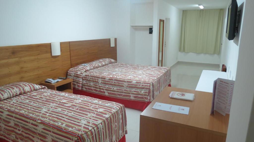 a hotel room with two beds and a desk at Atlântico Centro Apartments in Rio de Janeiro