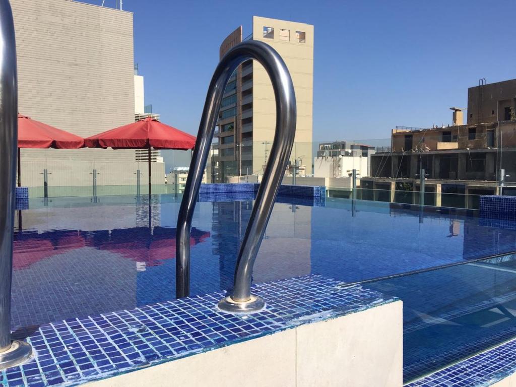 Midtown Hotel & Suites في بيروت: حمام سباحة مع سور معدني بجوار مبنى
