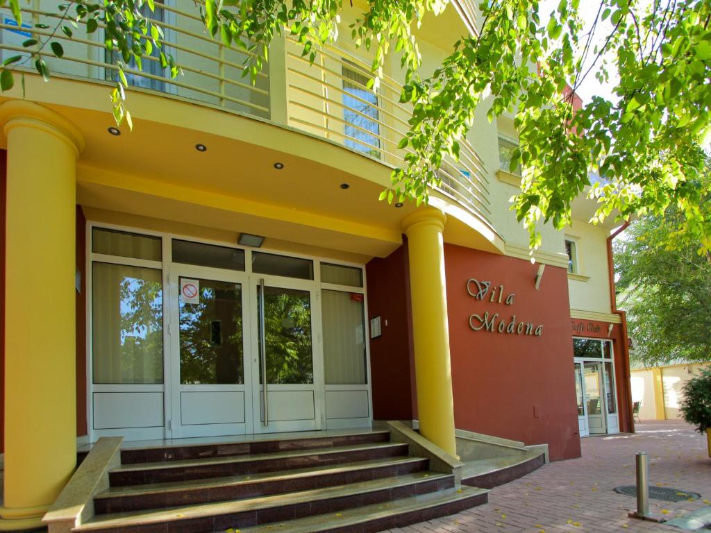 ein gelbes Gebäude mit einer Treppe davor in der Unterkunft Villa Modena in Subotica