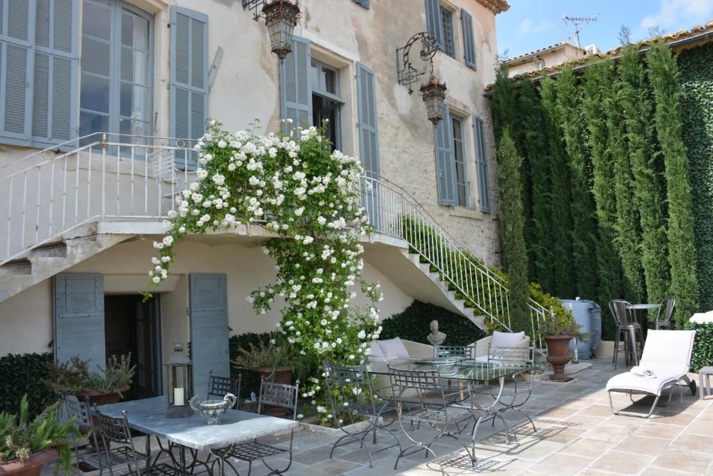 a patio with tables and chairs and flowers at Le Petit Chateau in Châteauneuf-de-Gadagne