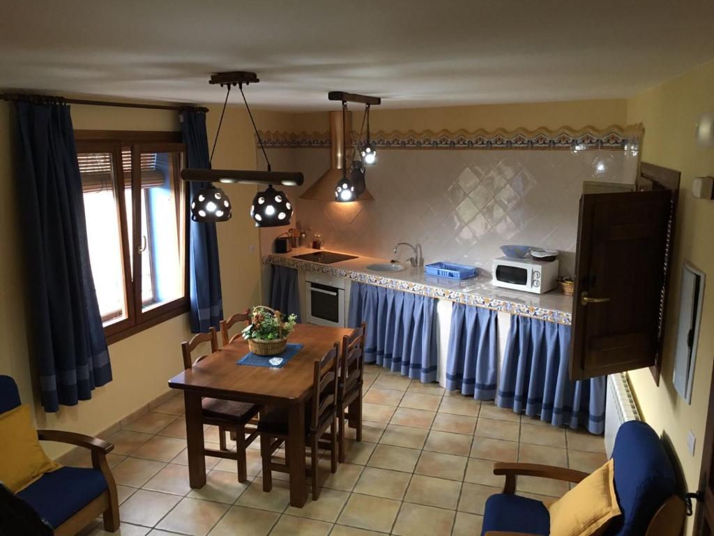 cocina con mesa y cocina con cortinas azules en Casa Rural Del Antiguo Hojalatero en Ibdes