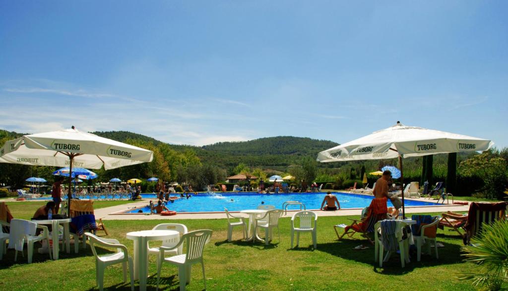 eine Gruppe von Stühlen und Sonnenschirmen neben einem Pool in der Unterkunft Lido Camping Village in Bolsena