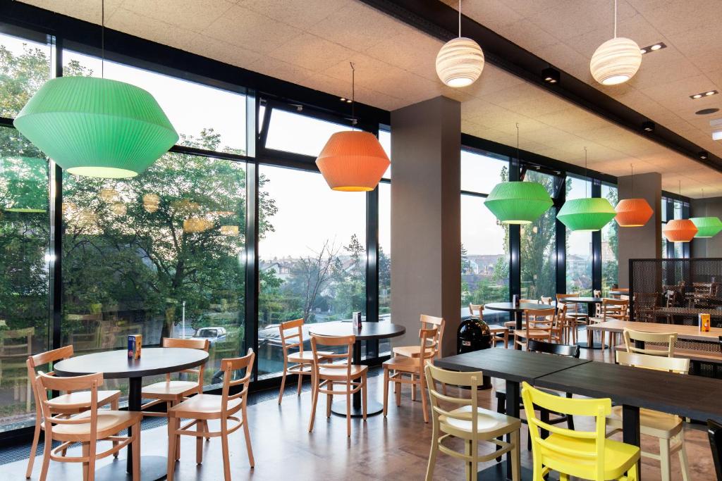 a restaurant with tables and chairs and large windows at a&o Prague Rhea in Prague