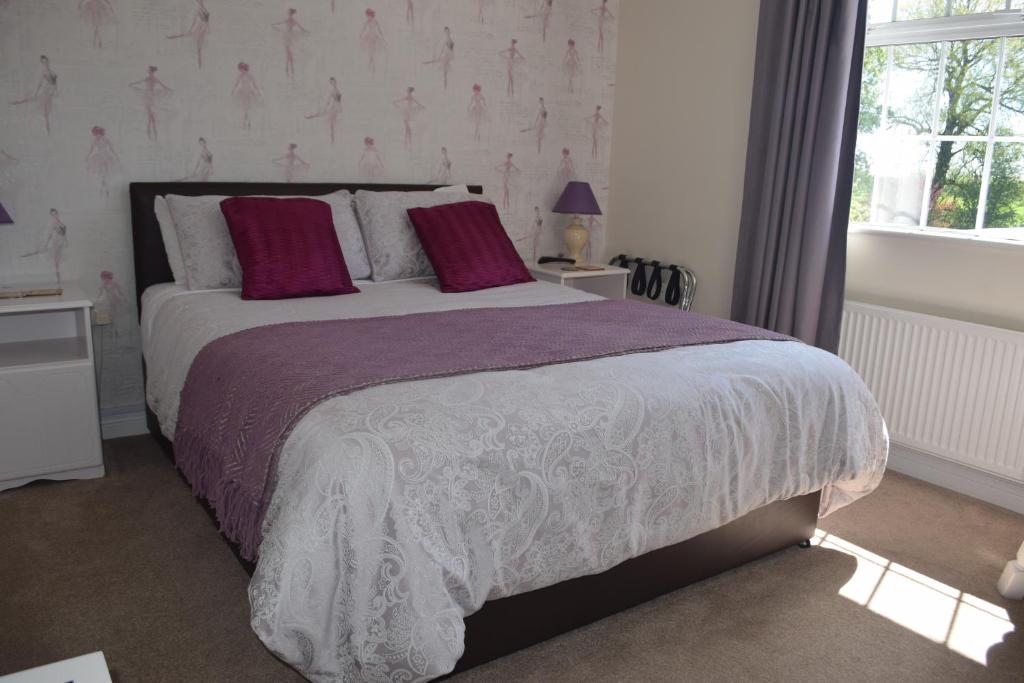 Un dormitorio con una cama con sábanas moradas y blancas y una ventana. en Orchard Grove bed & breakfast R21RC58 en Bagenalstown