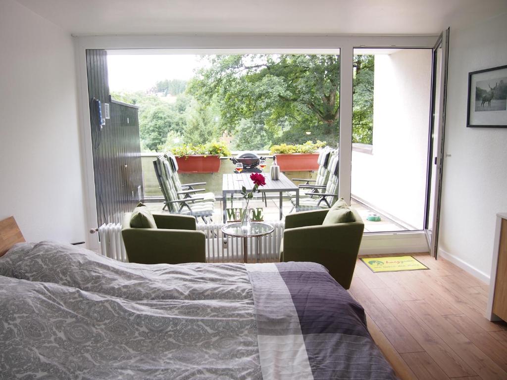 a bedroom with a bed and a balcony with a table and chairs at Apartment Harzgrün 2 in Sankt Andreasberg