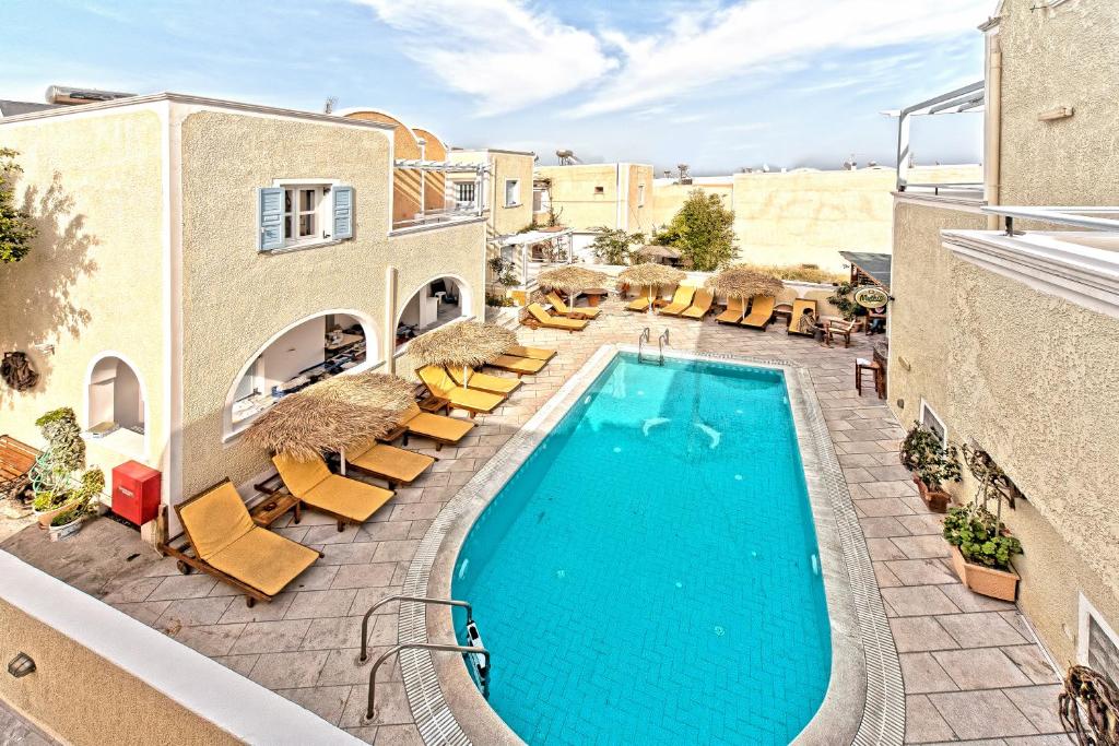 an image of a swimming pool with lounge chairs and a resort at Sellada Apartments in Kamari