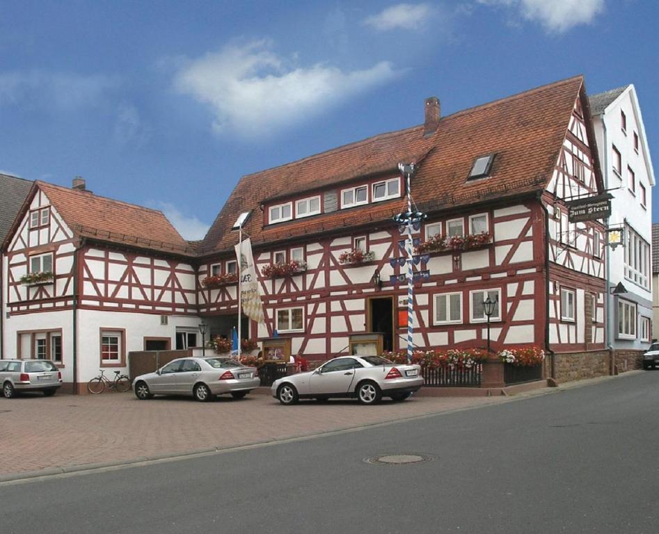 a large building with cars parked in front of it at Gasthof-Landhotel-Metzgerei Zum Stern in Rüdenau