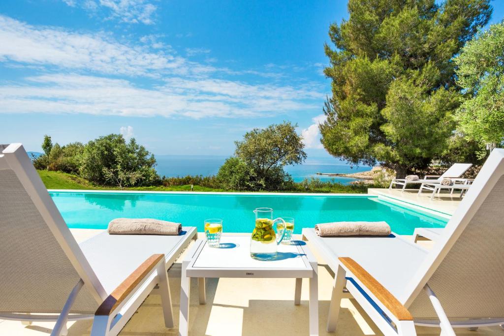 尼基季的住宿－A&A Luxury Beach Villas，游泳池畔的一张桌子和两把椅子