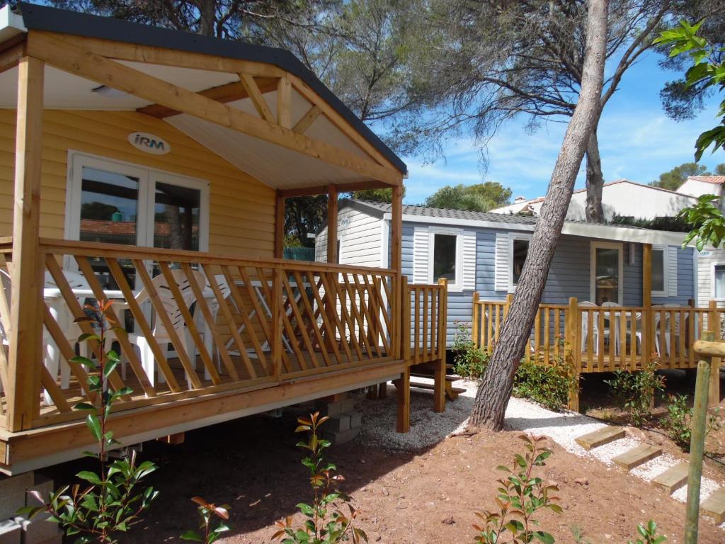 a house with a large wooden deck with a porch at Camping l'Eléphant in Saint-Raphaël