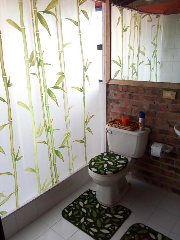 a bathroom with a toilet with a mural of bamboo at Refugio Explora Verde in Choachí