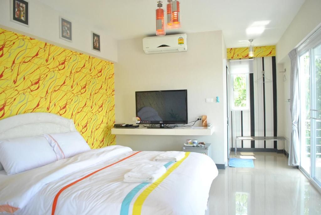 um quarto com uma cama e uma televisão na parede em O.U.M. Hotel - โรงแรมโอยูเอ็ม em Uttaradit