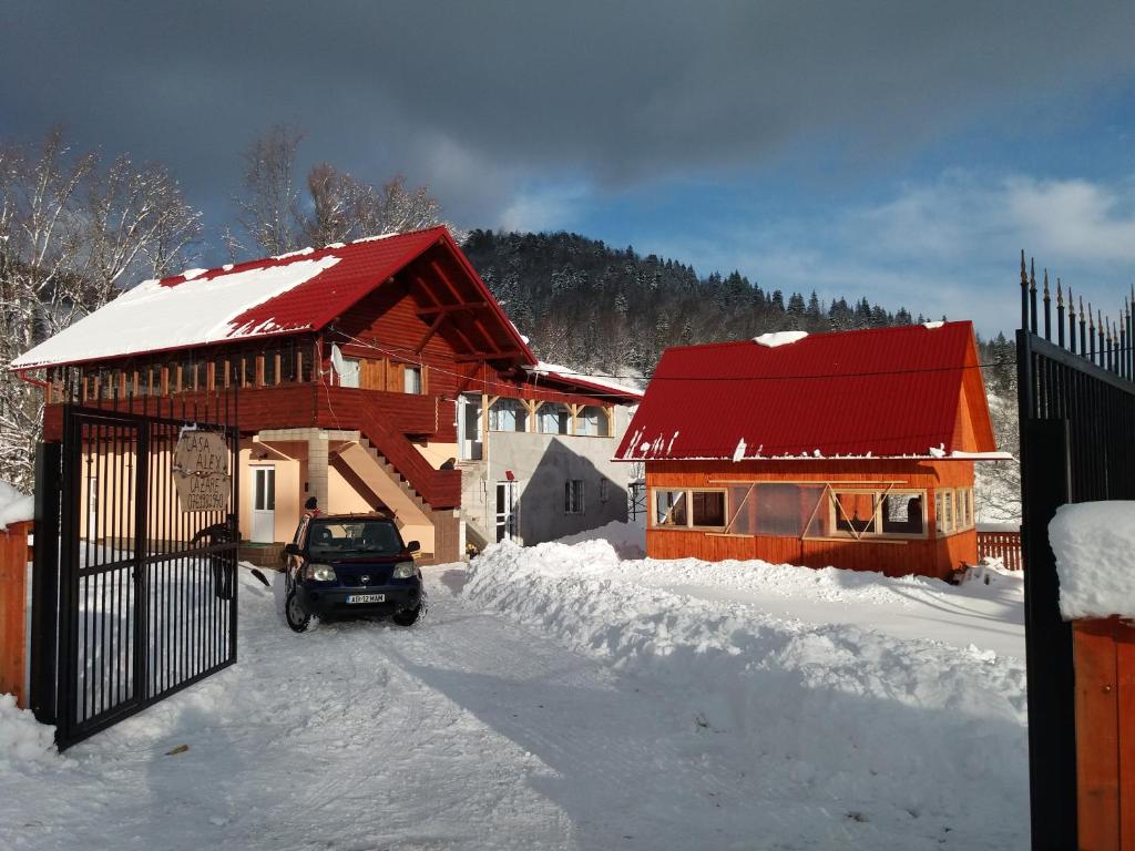 une voiture garée devant une maison dans la neige dans l'établissement Casa Alex, à Gîrda de Sus
