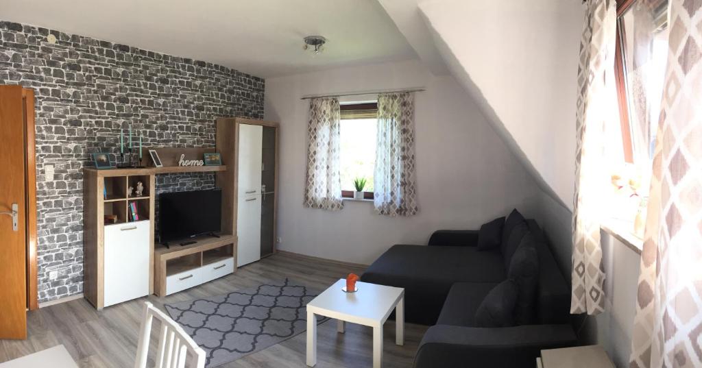 ein Wohnzimmer mit einem schwarzen Sofa und einem TV in der Unterkunft FeWo Haus Emma OG in Löhnberg