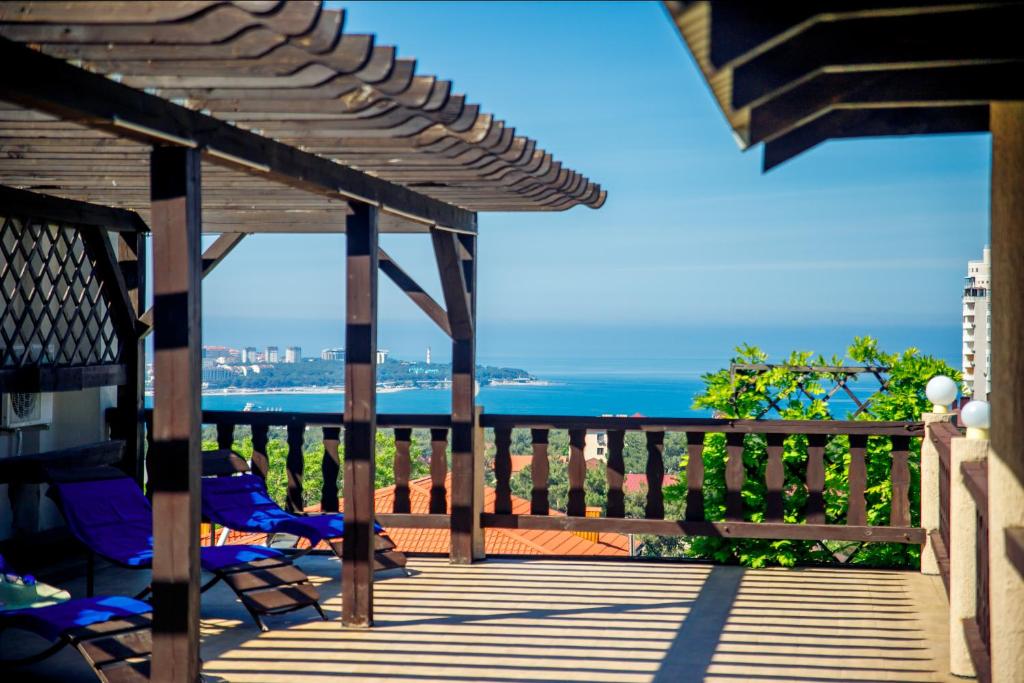 a wooden deck with chairs and a view of the ocean at Hotel Dombay in Gelendzhik