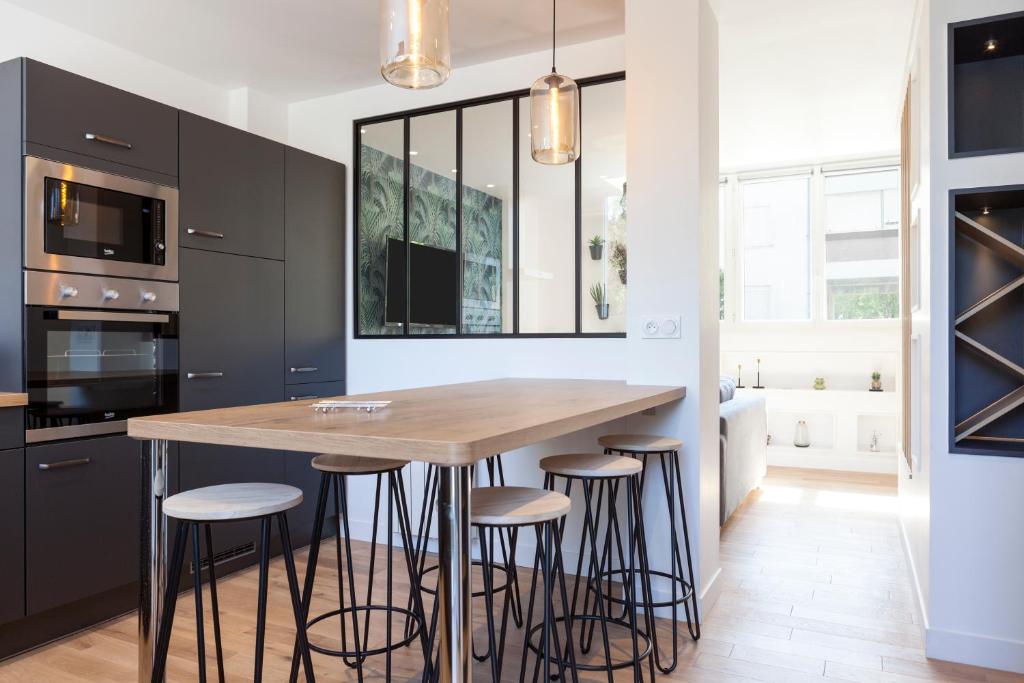 a kitchen with black cabinets and a wooden island with stools at Résidence Maréchal Leclerc in Laval