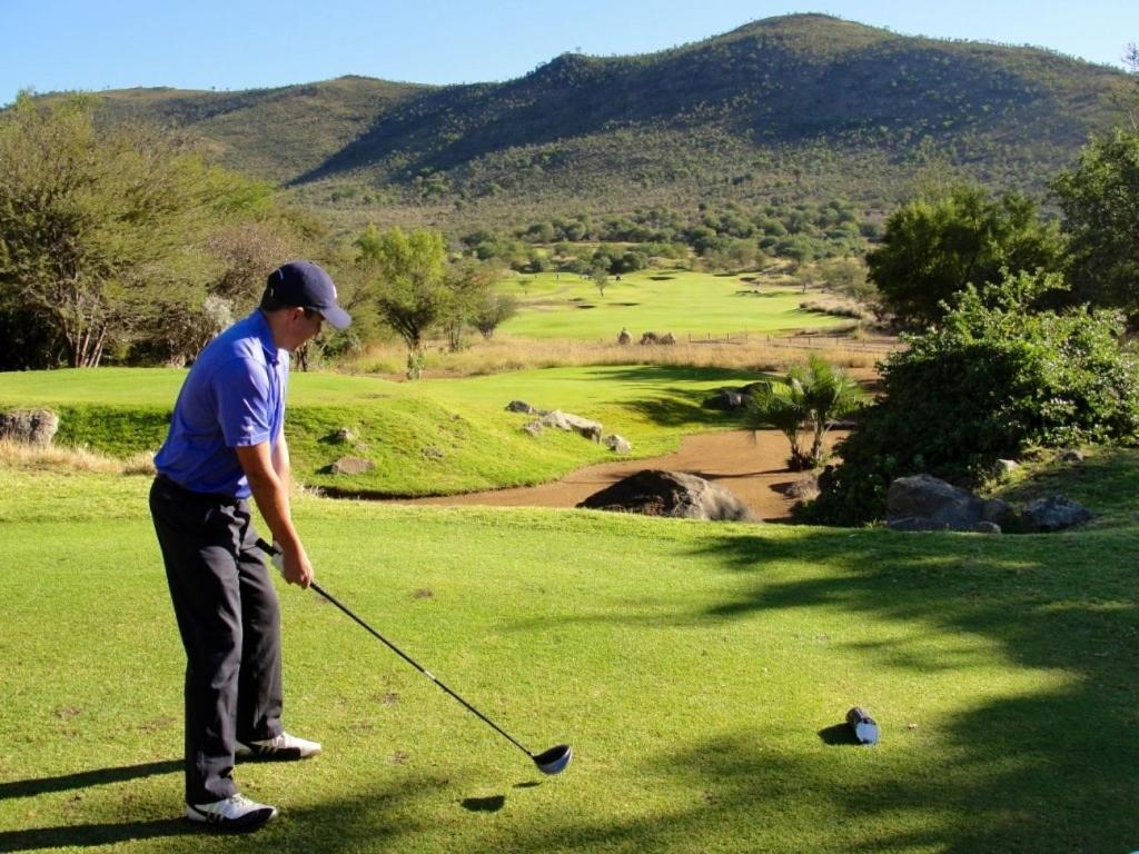 a man is playing golf on a golf course at Waterberg Accommodation in Modimolle