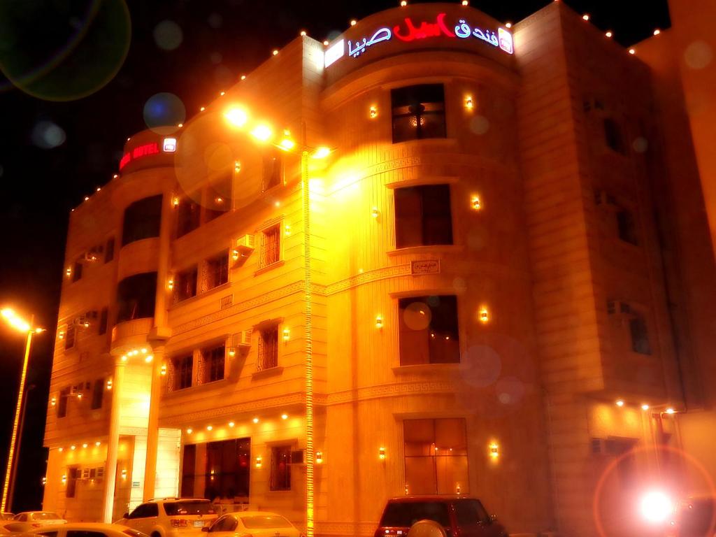 un edificio iluminado con un cartel encima en Aseel Hotel Apartment, en Jazan