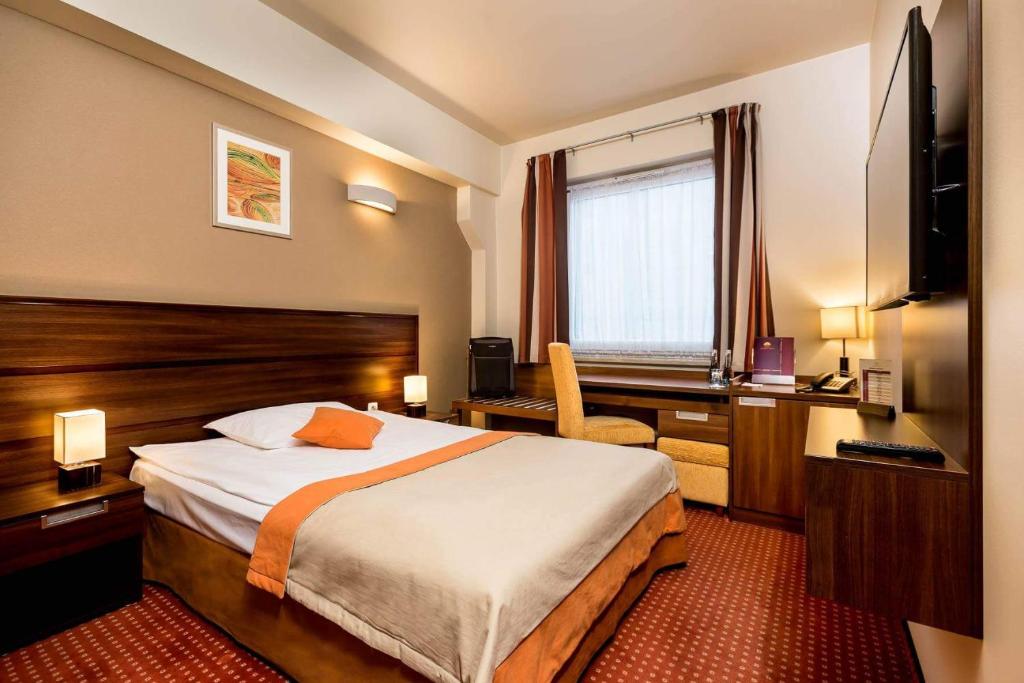a hotel room with a large bed and a desk at Hotel Tęczowy Młyn in Kielce