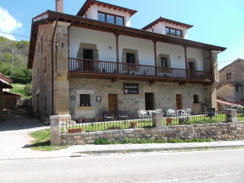 Pejanda的住宿－La Escuelona，街道上一座古老的石头建筑,设有阳台