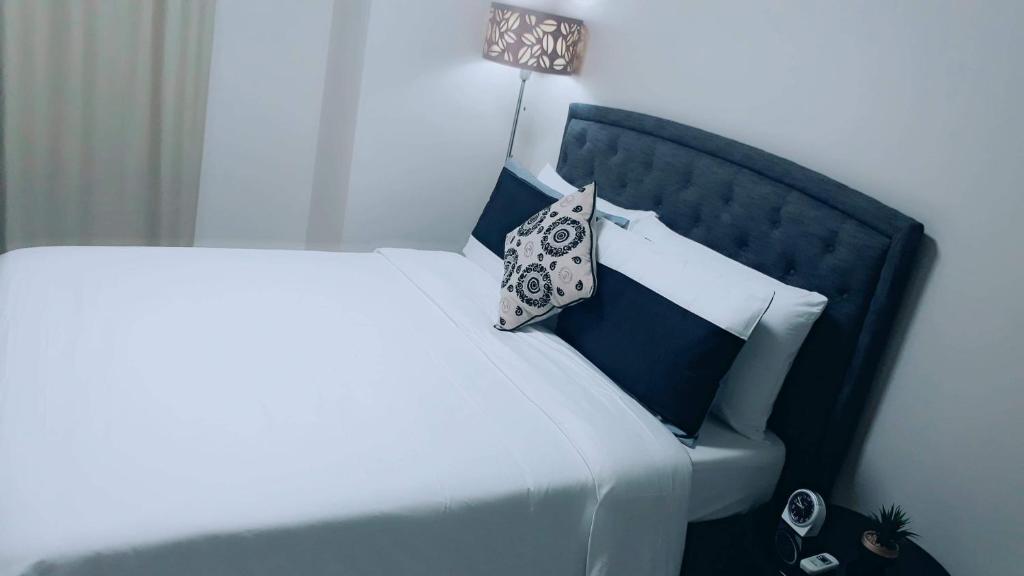 a white bed with a black headboard and a pillow at Newport City Condo near Manila Airport Terminal 3 in Manila
