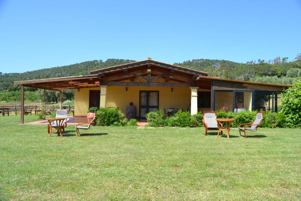 een huis met stoelen en tafels in het gras bij Pian di Rocca Country in Castiglione della Pescaia